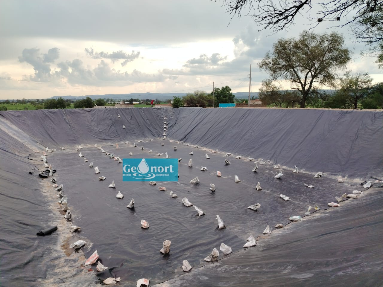 Perspectiva amplia de la superficie recubierta con geomembrana y distintivo de Geonort